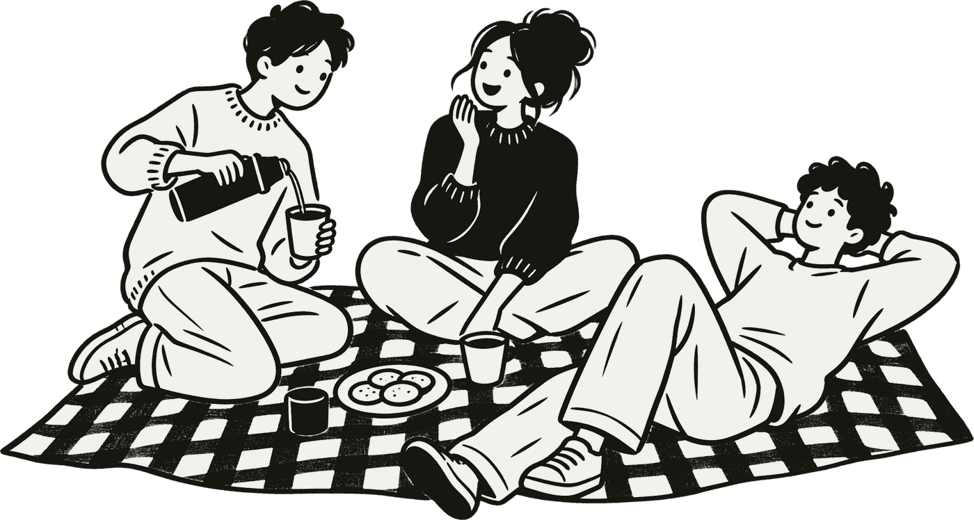 Three friends on a checked picnic rug, one pouring tea, one laughing, one lying back.